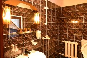 a black tiled bathroom with a sink and a mirror at House Shiligarnika in Bansko