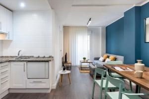 eine Küche und ein Wohnzimmer mit einem Tisch und einem Sofa in der Unterkunft Espíritu Santo Suite Apartment in Sevilla