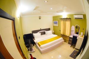 AroにあるRemzy Hotel & Suites, Olomoreのベッドルーム1室(大型ベッド1台、黄色と白の枕付)