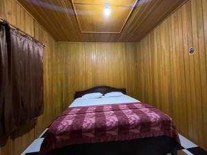 a bedroom with a bed in a wooden room at THE SINGKI HOME FAMILY in Rantepao