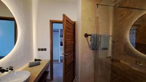 La salle de bains est pourvue d'un lavabo et d'une douche en verre. dans l'établissement Aluna Beach Apartments, à Nungwi
