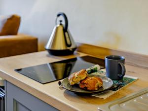 a plate of muffins and a cup of coffee on a kitchen counter at 1 Bed in Tiverton 90656 in Washfield