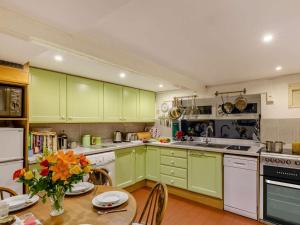 a kitchen with green cabinets and a table with flowers at 3 Bed in Bishops Castle 90644 in Bishops Castle