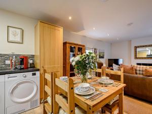 a kitchen and living room with a wooden table with flowers at 2 Bed in Falkirk 90602 in Bonnybridge