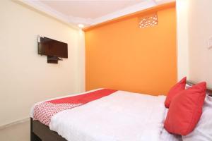 een slaapkamer met een bed met rode kussens en een televisie bij OYO Hotel Vn Residency in Jabalpur