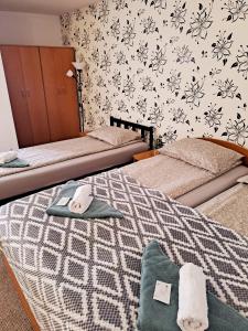 a bedroom with two beds and a wall with flowers at 7 Levél Panzió, Ultra Central, Self Check-in, Self-Catering in Miercurea-Ciuc