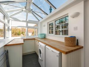 a conservatory kitchen with a washer and dryer at 3 Bed in Sheringham 90701 in Sheringham