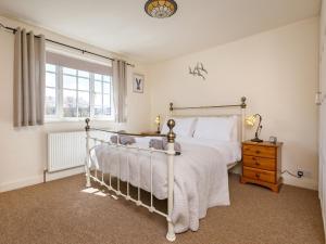 a bedroom with a white bed and a window at 3 Bed in Sheringham 90701 in Sheringham