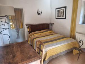 ein kleines Schlafzimmer mit einem Bett und einem Tisch in der Unterkunft Grand Mas Provençal avec jacuzzi in Sisteron