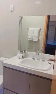 a bathroom with a white sink and a mirror at Flat vista mar em Santos in Santos