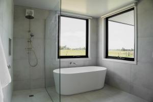 ein weißes Bad mit einer Badewanne und 2 Fenstern in der Unterkunft Dalrose Retreat in Stratford
