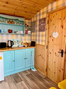 a kitchen with blue cabinets and a wooden wall at Shepherds hut Greencastle in Omagh