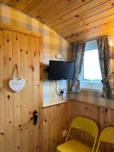 a room with wooden walls and a tv and a yellow chair at Shepherds hut Greencastle in Omagh