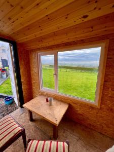 a room with a table and a large window at Shepherds hut Greencastle in Omagh
