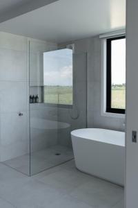 ein weißes Bad mit einer Badewanne und einem Fenster in der Unterkunft Dalrose Retreat in Stratford