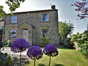 an old stone house with purple flowers in front of it at 3 Bed in Richmond 90578 in Catterick Bridge