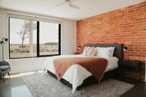 Schlafzimmer mit Ziegelwand und großem Bett in der Unterkunft Dalrose Retreat in Stratford