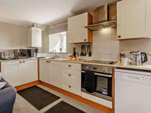 uma cozinha com armários brancos e um forno com placa de fogão em 3 Bed in Cosheston 90732 em Cosheston