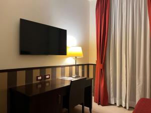 a hotel room with a desk with a television on the wall at Hotel Garda in Rome