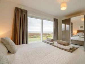 a bedroom with a large white bed with a large window at 1 Bed in Aberdesach 90624 in Clynnog-fawr