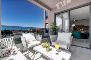 a balcony with two chairs and a table with wine glasses at Villa Bomada in Tučepi