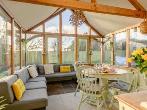 a conservatory with a couch and a table and chairs at 4 Bed in Blakeney 90589 in Awre