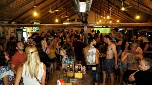 a crowd of people standing around a bar in a room at The Big Easy Koh Rong Samloem in Koh Rong Sanloem