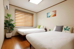a bedroom with two beds and a potted plant at さくらや旅館 in Mongawa