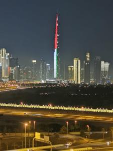 a city skyline at night with a red and green sign at Burj Khalifa & City Skyline View, Full Furnish Studio in Dubai