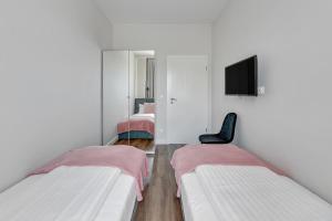 a white room with two beds and a chair at Scala Apartamenty by Moderna Profit- Łąkowa 60C- Parking in Gdańsk