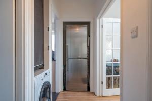 a stainless steel refrigerator in a kitchen next to a door at Madika Homes - Cosy Edgware 2 Bed Flat with Free parking in Edgware