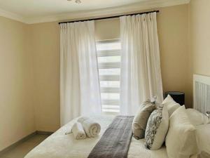 1 dormitorio con cama con almohadas y ventana en Wanderlust 2-bedroom Apartment, en Centurion