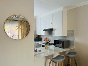 a kitchen with a clock on the wall and two stools at Wanderlust 2-bedroom Apartment in Centurion