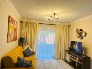 a living room with a yellow couch and a television at Wanderlust 2-bedroom Apartment in Centurion