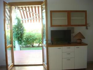 ein Wohnzimmer mit einem TV und einer Glasschiebetür in der Unterkunft Villetta Cinquale Versilia in Cinquale