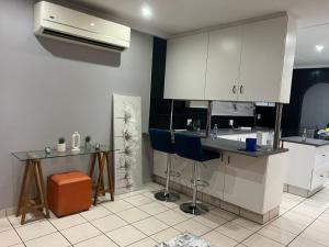 a kitchen with white cabinets and blue bar stools at When in the Middle Self Catering Guest House in Durban
