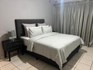 a bed with white sheets and pillows in a bedroom at When in the Middle Self Catering Guest House in Durban
