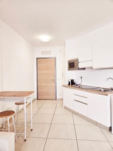 una cucina con armadi bianchi, tavolo e sedie di Dolphin's Home a Porto Torres