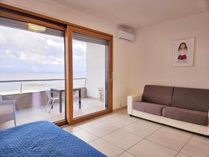 una camera da letto con divano, tavolo e balcone di Dolphin's Home a Porto Torres