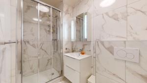 a white bathroom with a shower and a sink at Modern studio in the heart of Geneva in Geneva