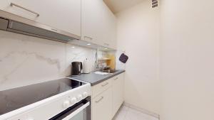 a white kitchen with a sink and a stove at Modern studio in the heart of Geneva in Geneva