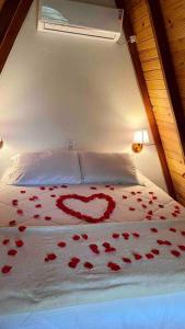 ein Bett mit roten Rosen und einem Herz darauf in der Unterkunft Chalé de madeira com vista para o rio in Pomerode