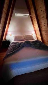 uma cama num pequeno quarto com duas luzes em Chalé de madeira com vista para o rio em Pomerode
