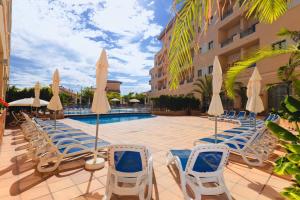 a swimming pool with lounge chairs and umbrellas at Hotel Monarque Costa Narejos in Los Alcázares