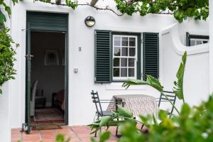 uma casa branca com uma janela, uma mesa e cadeiras em Eikendal Lodge em Stellenbosch