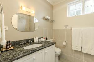 W łazience znajduje się umywalka, toaleta i lustro. w obiekcie Eikendal Lodge w mieście Stellenbosch