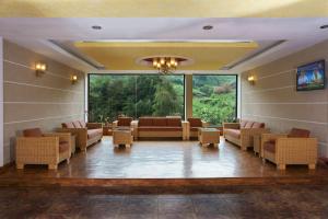 Hotel C7 Munnar في مونار: غرفة انتظار مع كنب وكراسي ونافذة كبيرة