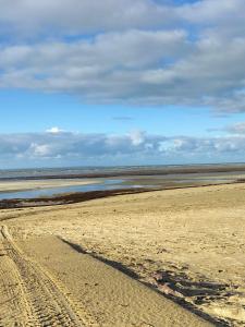 einen Strand mit Fußabdrücken im Sand und einem Wasserkörper in der Unterkunft Le goéland in Créances