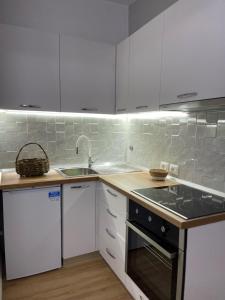 uma cozinha com armários brancos e um forno com placa de fogão em Beratinus Apartment em Berat