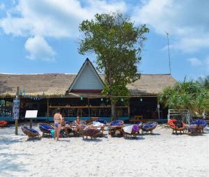 高龙撒冷岛The Big Easy Koh Rong Samloem的一群人坐在沙滩上的椅子上